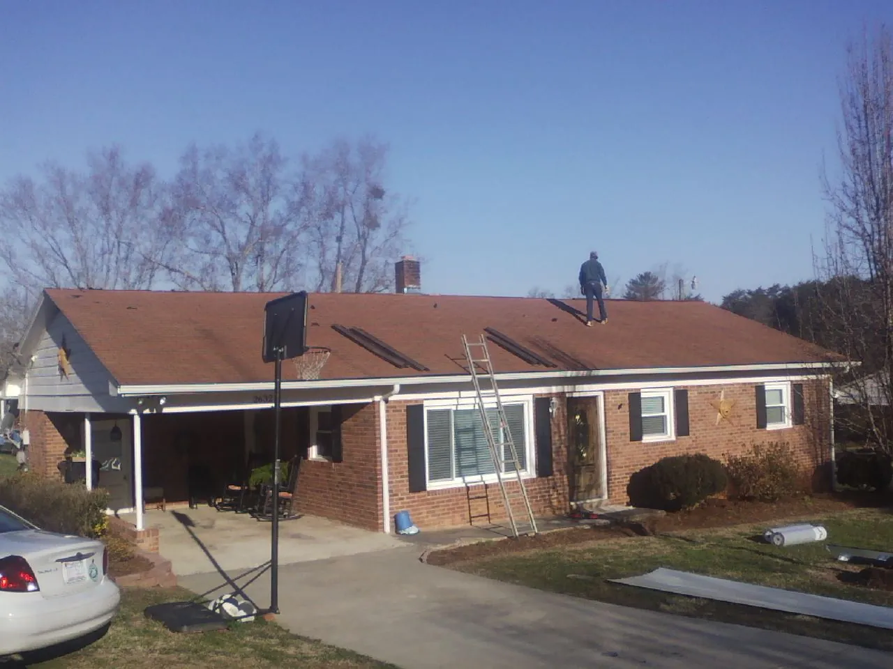 Roofer stripping a shingle roof on a brick ranch before metal panels in Parker